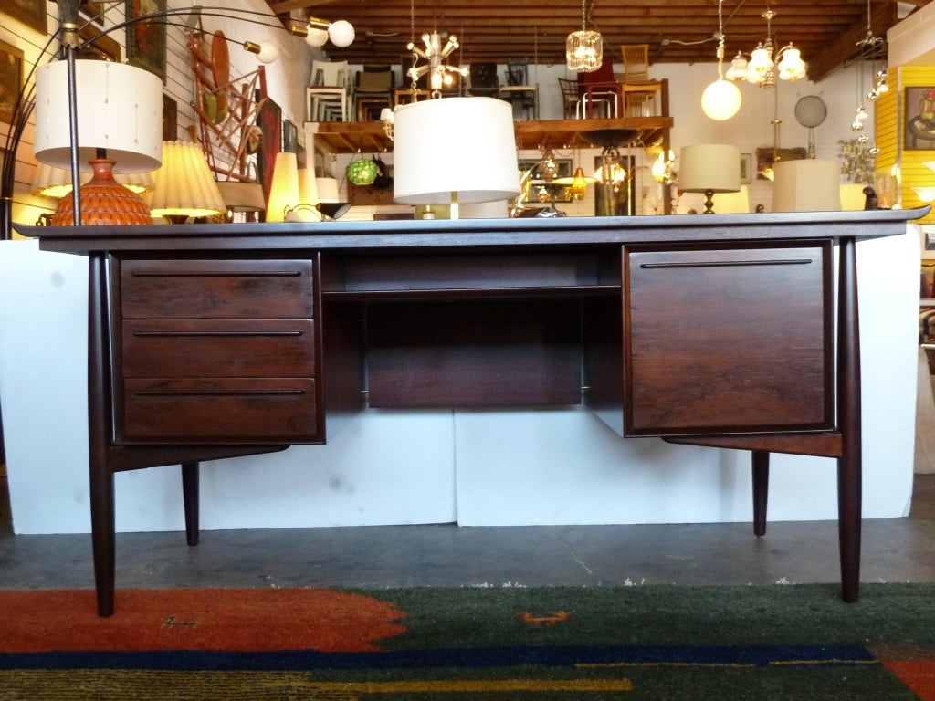 This Danish rosewood desk from the 1960s has an open storage compartment on each side. On the front there are three drawers on one side and a file drawer on the other. The edges of the top gently curve up to emphasize the open structure of the frame.