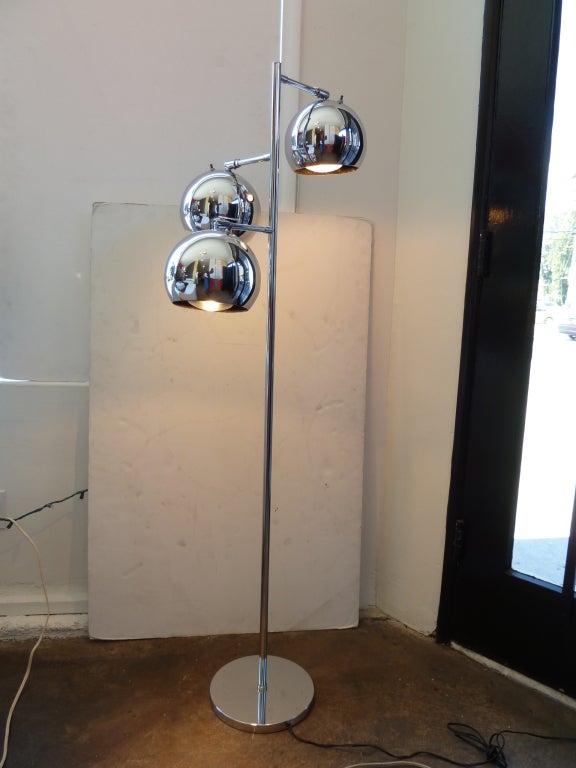 This chrome floor lamp features three large globes at varying heights. Each fixture has an individual on / off switch and may be adjusted up and down. The spine of the lamp is circular as is the base.