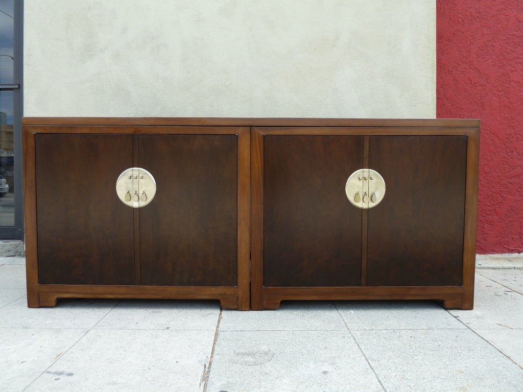 This two-tone storage buffet features circular brass medallions with decorative pulls on the front of each set of doors. On one side of the buffet, the doors open up to divided shelving, while behind the other doors lies a set of multiple drawers.