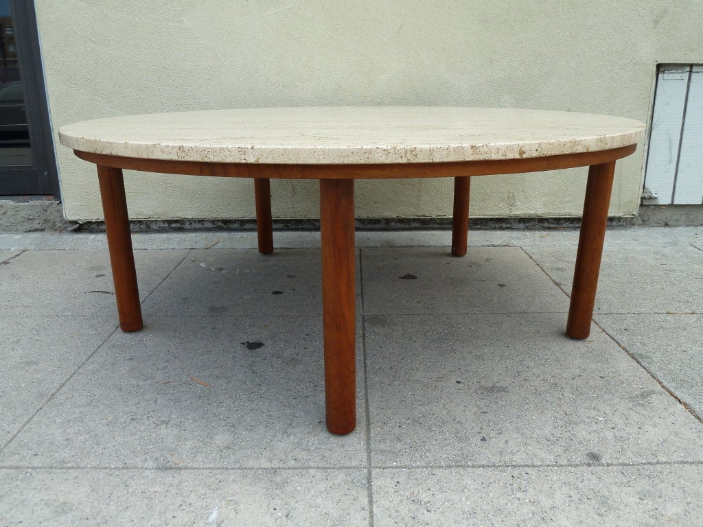 This round coffee table features a thick travertine top which rests on a walnut base supported by five pillar legs.