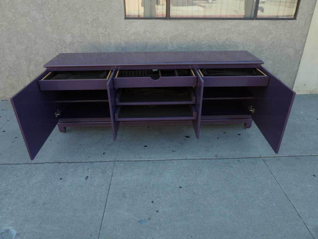 This commanding four door credenza features a rich finish, inside and out, in aubergine lacquer. The unit boasts plenty of storage including three drawers along the top with multiple shelves beneath, some of which pull out. 
The credenza rests on a