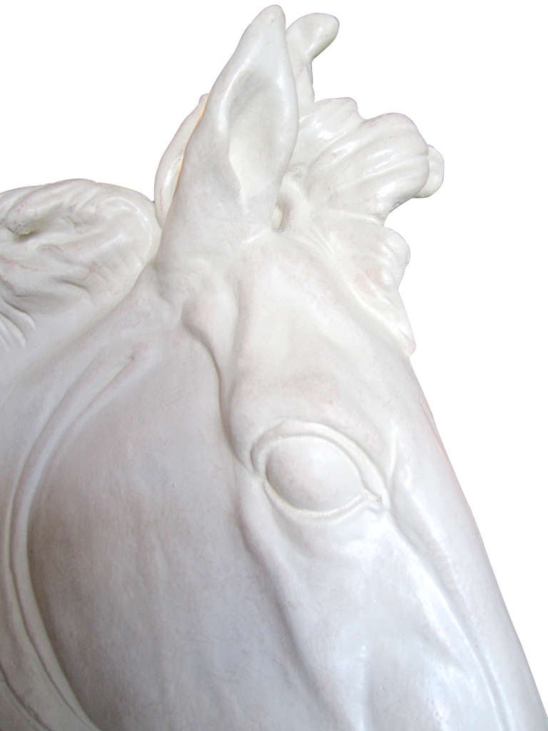 This dynamic, decorative sculpture of a horse's head in plaster features a subtle iridescent sheen. The monumental sculpture, which is almost life-size, will add a chic dramatic element to any space.