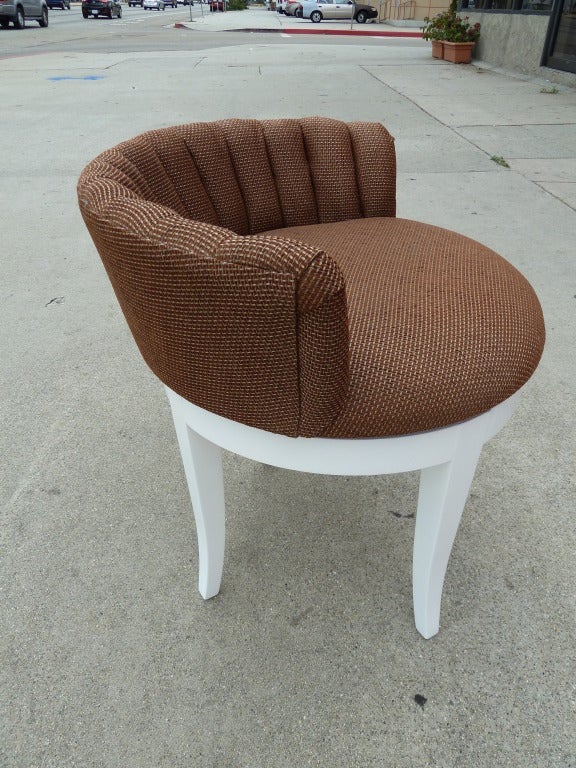 The swivel seat has been upholstered in a gold and brown pattern and the wooden tapered legs are laquered in white. The back is very low, and the seat is 17” high.