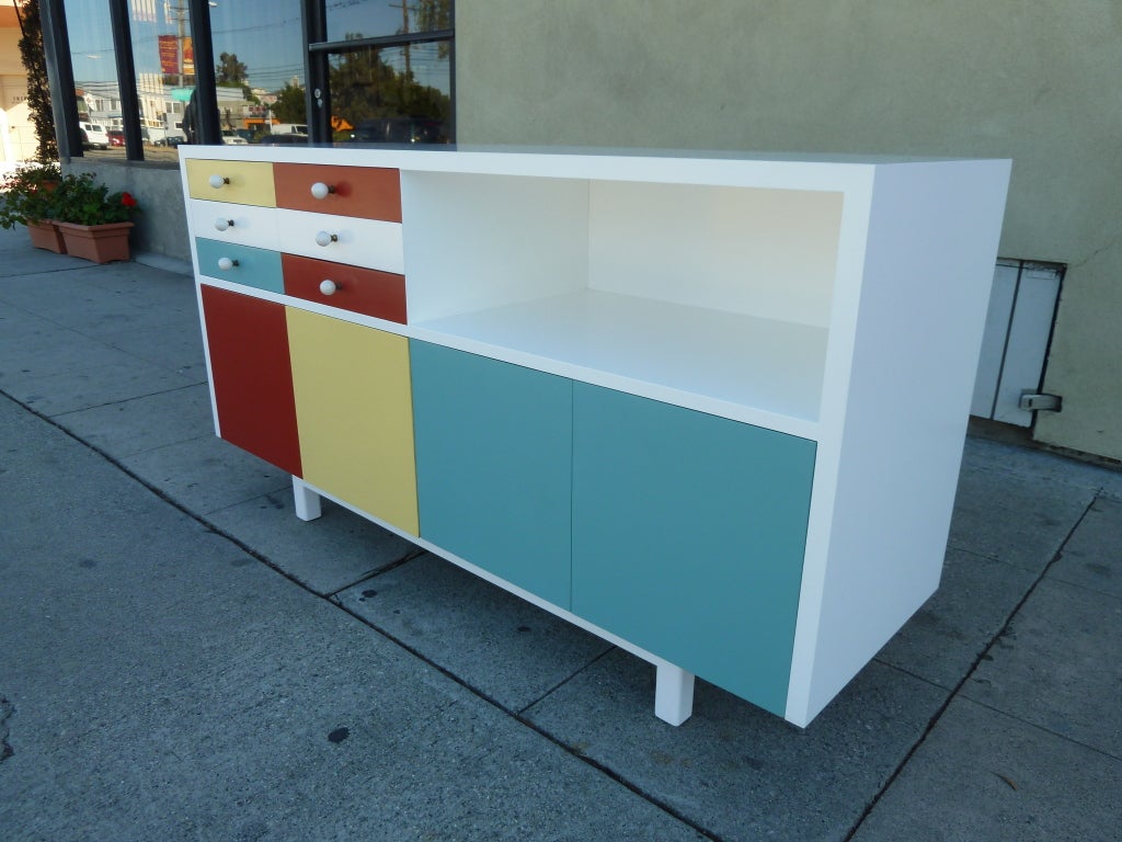 This playful mid-century modern cabinet features plenty of useful storage. The top section offers six drawers on the left and an open space for books or objects on the right; the lower half is made up of four capacious filing drawers. The colorful
