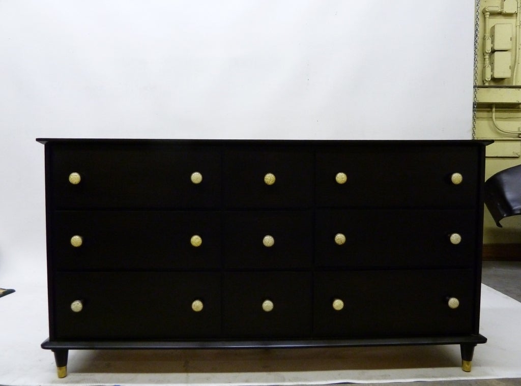 This nine drawer dresser by Spainhour features solid maple construction and is stained a rich espresso color. The unusual brass handles are filled with a granulated resin; the ends of the tapered legs are fitted with brass caps.
The piece is