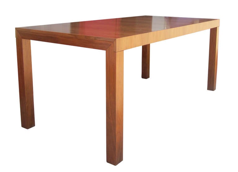 The rectilinear design of this mid-century modern dining table is emphasized by the manner in which the table expands. The top of the table is made of two sliding surfaces that reveal an attached, hidden folded extension when you open them. This