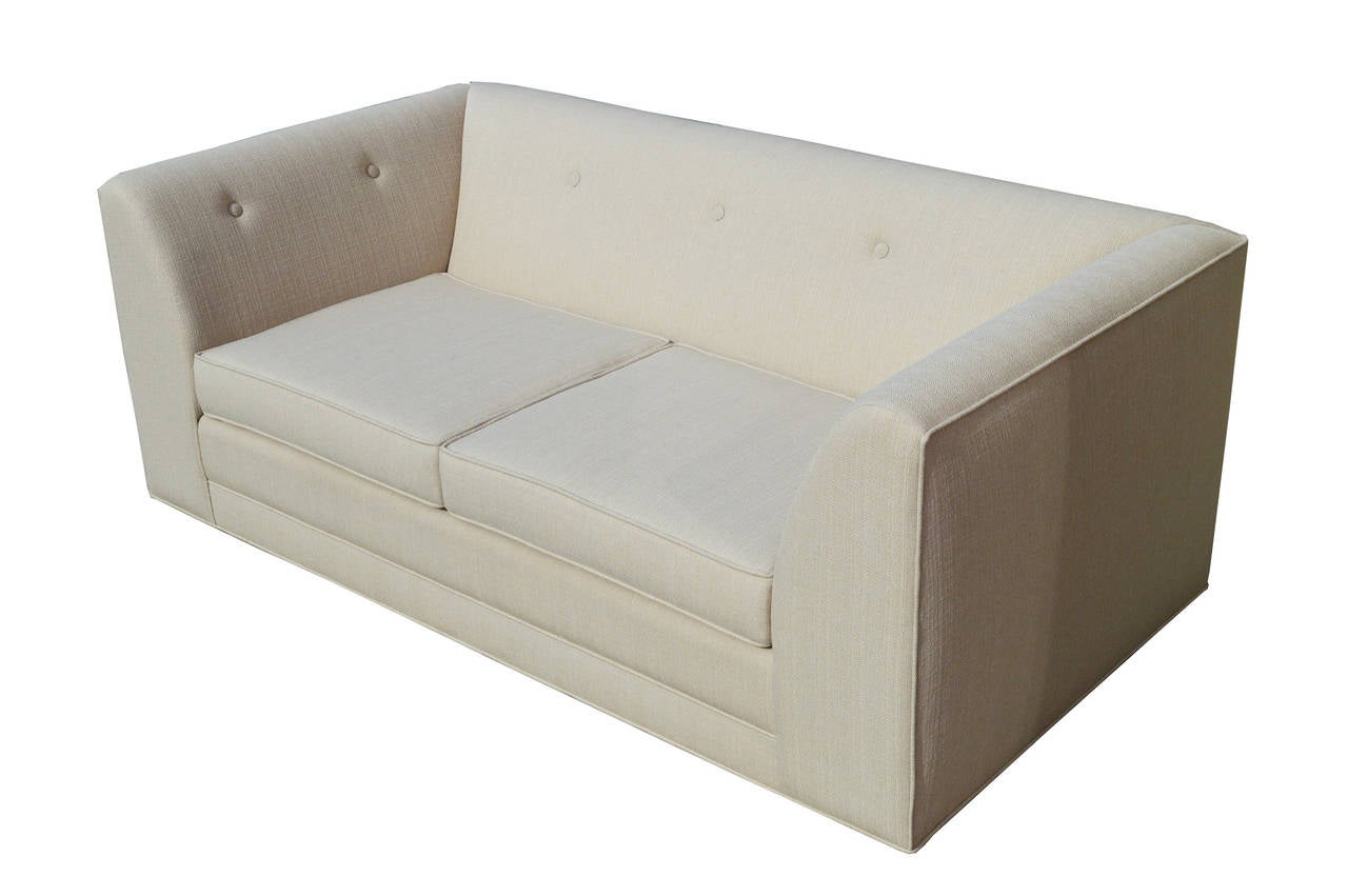 A 1960s comfy loveseat with clean lines and minimalist detailing. Re-upholstered in soft light grey canvas.