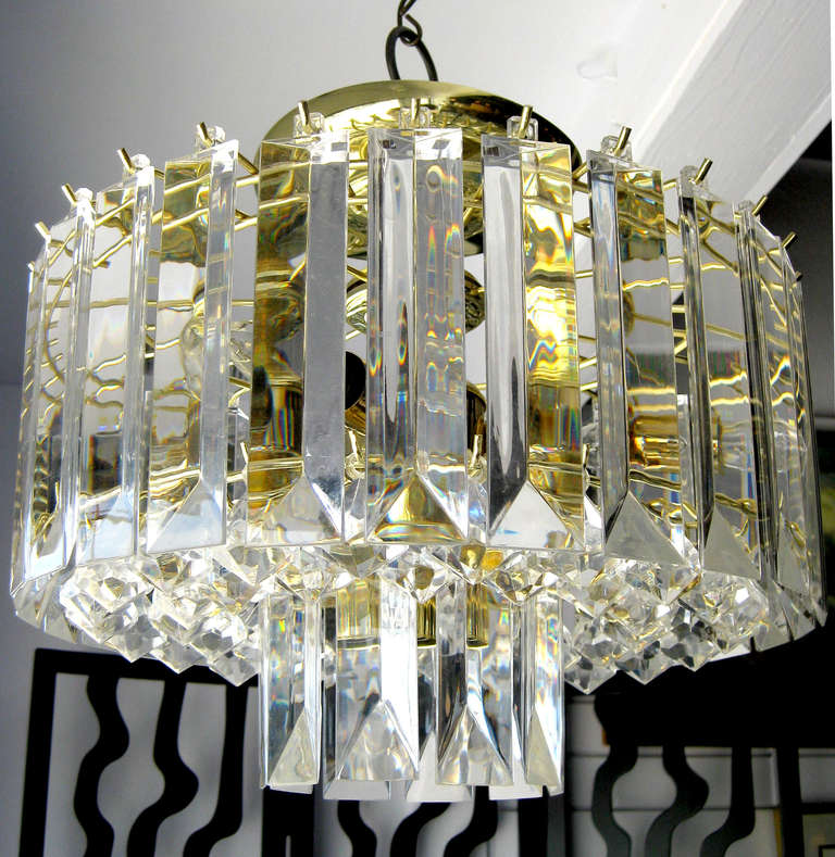 A Mid-Century Modern chandelier featuring three planes of Lucite dangles. The outermost and innermost planes support long, rectangular Lucite prisms and the central tier has two rings of teardrop-shaped faceted Lucite crystals. The minimal frame and