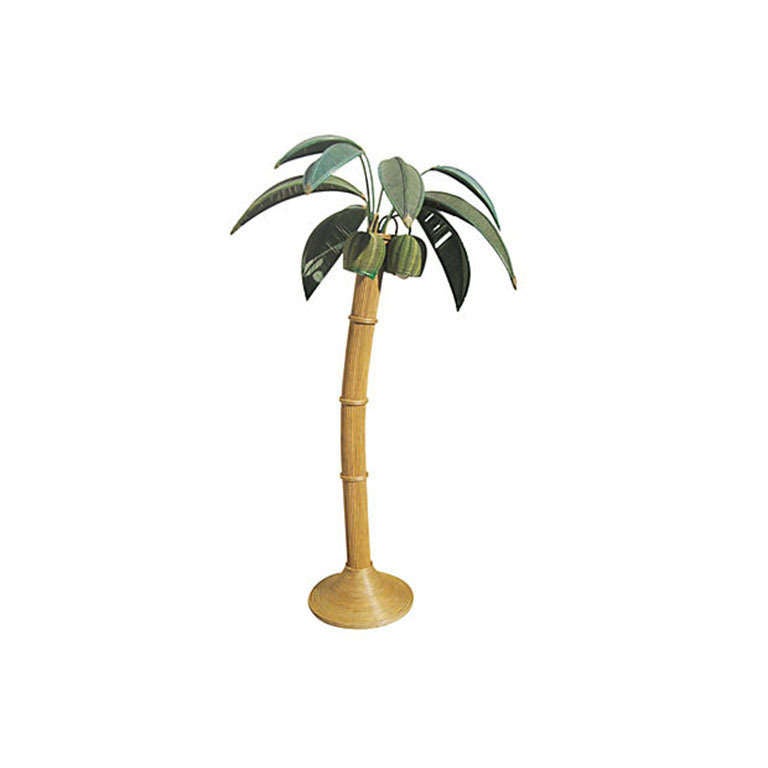 This floor lamp features a rattan and bamboo frame in the shape of a palm tree. The leaves of the tree can be removed and arranged as desired. The lamp is wired and in working condition.