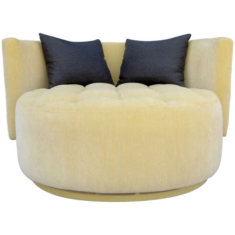 This large-scale lounge chair features a deep, circular seat that rests upon a well-controlled swiveling base. The recessed, tufted seat is halfway encircled by a backrest upholstered in the same butter yellow chenille microfiber. Includes two