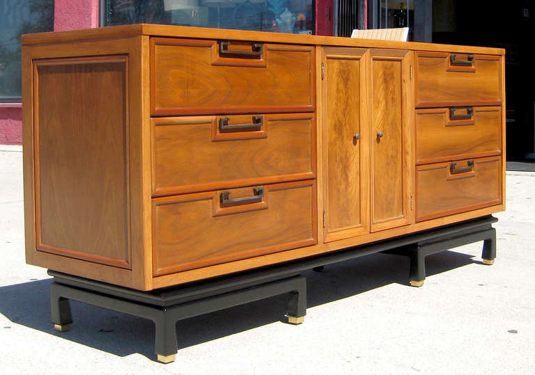 This American of Martinsville dresser is made of walnut with black lacquered base.The central doors open to reveal three file drawers, and this central section is flanked by three drawers on each side. Drawer on left side marked inside, 