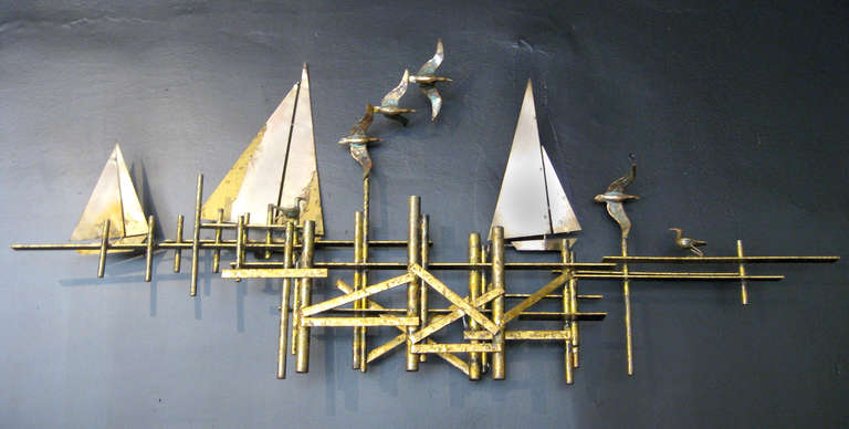 A metal wall sculpture by Curtis Jere featuring a Brutalist base, three sailboats, and five seagulls. The mostly brass sculpture is signed at the lower right, 