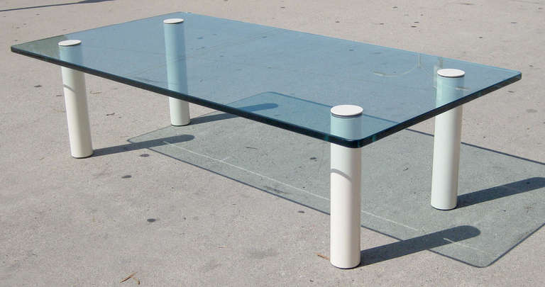 This coffee table features a rectangular glass top with four attached metal legs that are screwed into the glass from either side.