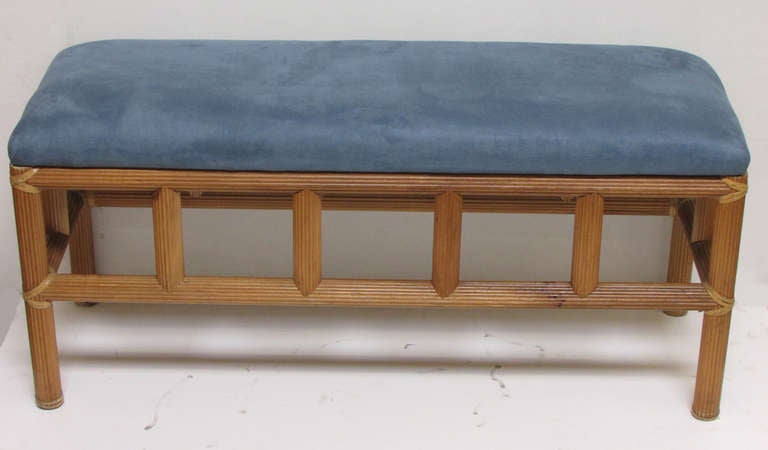 This petite bench features a sturdy base of carved wood and leather straps at the corners. It is surmounted by a single cushion in cornflower blue microfiber.