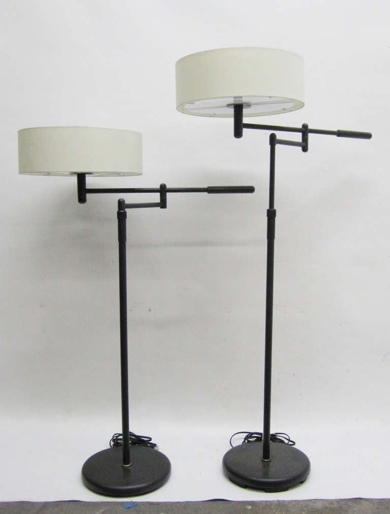 This handsome pair of floor lamps are height-adjustable with swing-arms to direct lighting. The base is made of patinated  gun metal with fabric shades and acrylic diffusers. The lowest height the lamps reach is 42 inches tall.