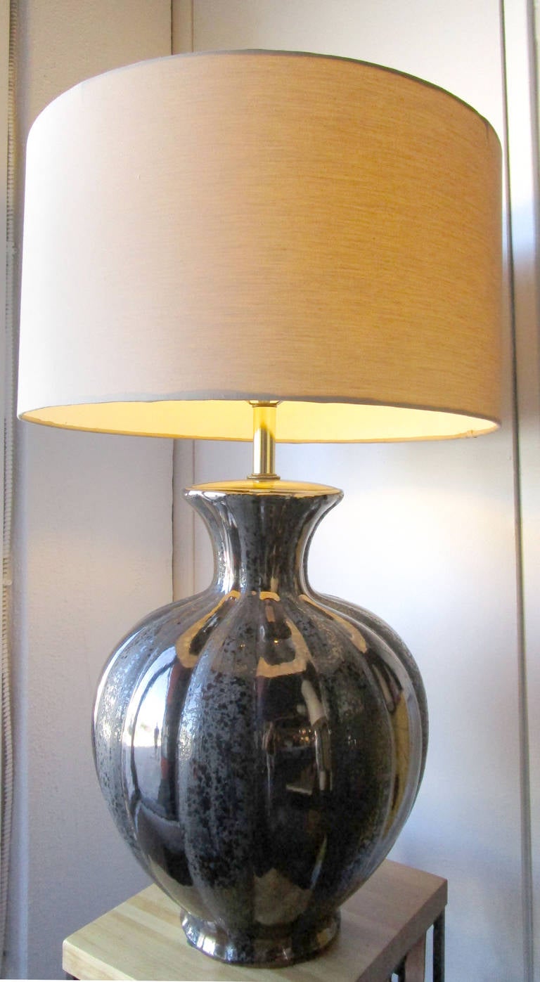 This glamorous metallic table lamp features a large, rounded base with alternating bands of smooth and textured shine. The gunmetal-toned top supports a brass harp and finial.Custom made shade measurements, 20