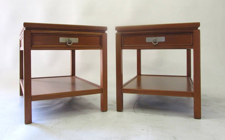 This pair of side tables or nightstands features beautiful natural wood grain surfaces and open frames. Each table has a single pull-out drawer with a brass pull.