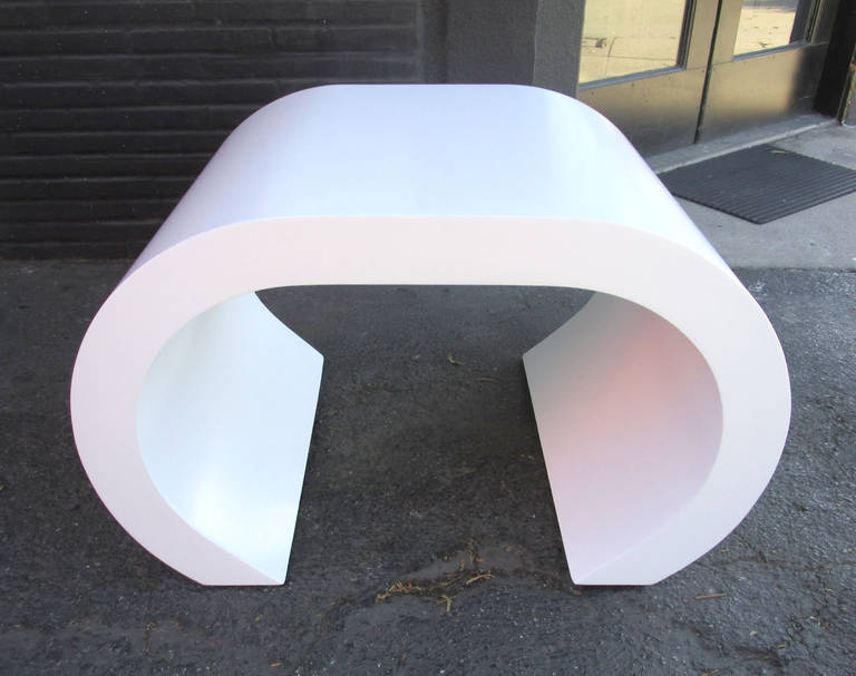 This chic white scroll coffee table or side table has been recently refinished in white lacquer. The elegant scroll shape and thickness of this piece bring to mind the 1970s designs of Karl Springer.