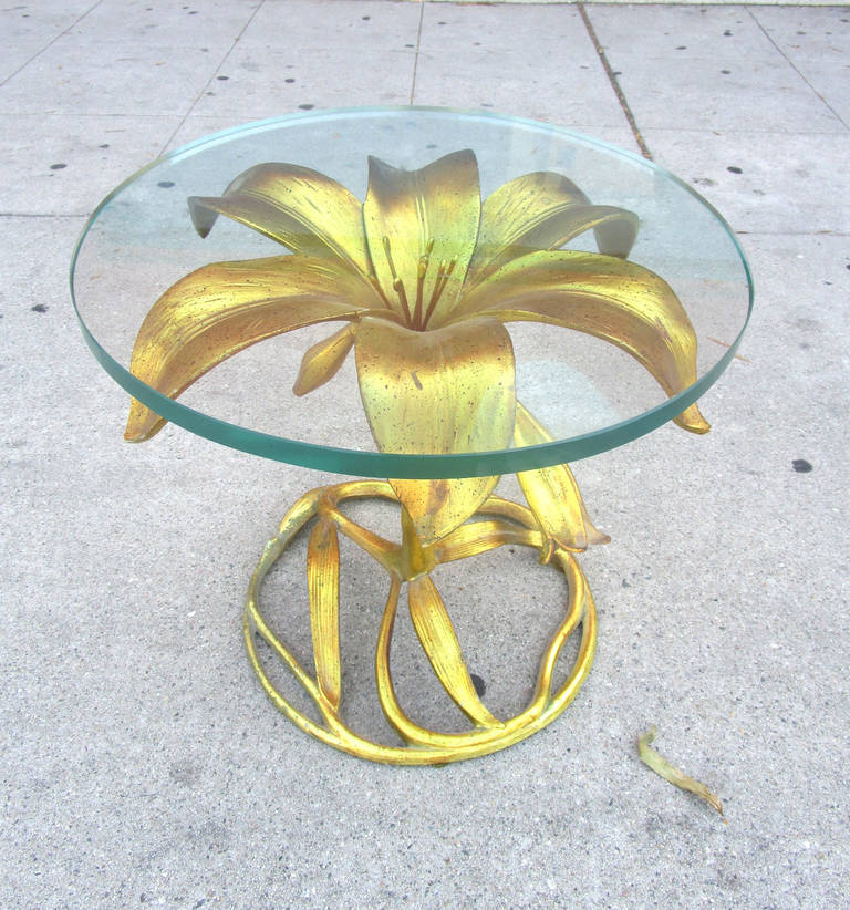 This Hollywood Regency side table by Arthur Court features a gilded aluminum base in the form of a lily. This base supports the thick, original circular glass.