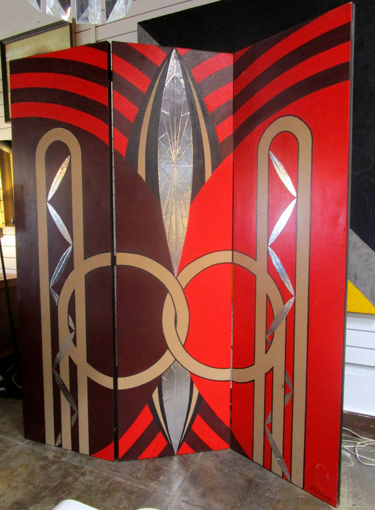 This fabulous art deco style screen or room divider is hand-painted onto three equally-sized canvas sections. The design, featuring stylized leaves and sweeping forms, is rendered in brown, red, tan and silver oil paint. This piece is signed at the