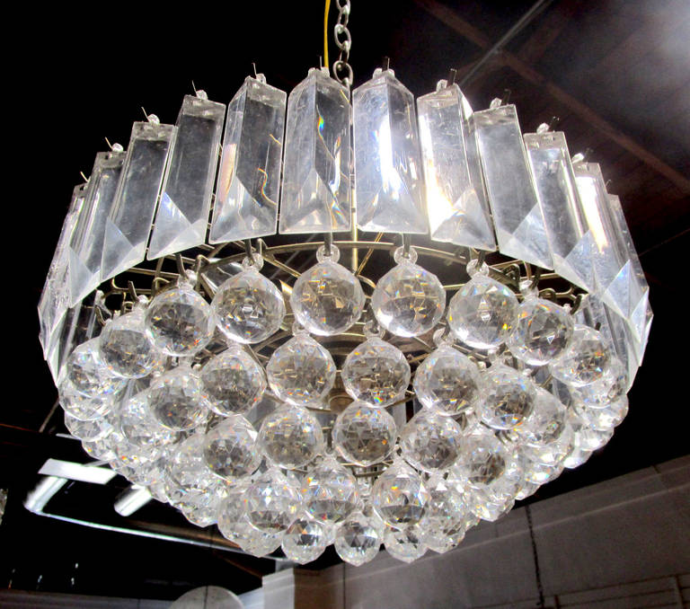A petite Lucite chandelier featuring a central section of faceted baubles that is framed by a ring of triangular Lucite prisms. The dangles hang from a brass frame.
Please contact the showroom about a matching, larger version of this piece.