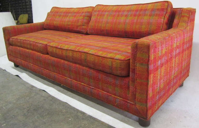 This stylish sofa made in the late 1960s by Cal-Mode features its amazing original plaid fabric which combines a panoply of colors including orange, red and chartreuse. 
The sofa boasts hard-wood, double dowel frame construction that is sure to