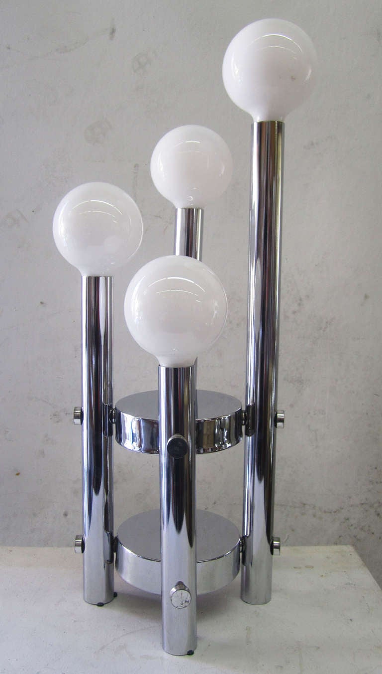This attractive lamp features four globular lightbulbs arranged in a tiered, cascading spiral atop a chrome base. An on/off switch is located in the middle of the base.