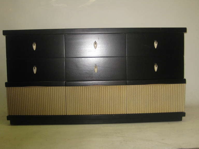 This rare mid-century dresser by American of Martinsville offers plentiful storage with nine drawers. The ebonized mahogany body is embellished with a reeded section near the bottom, which function as the third row of drawers. The top six drawers