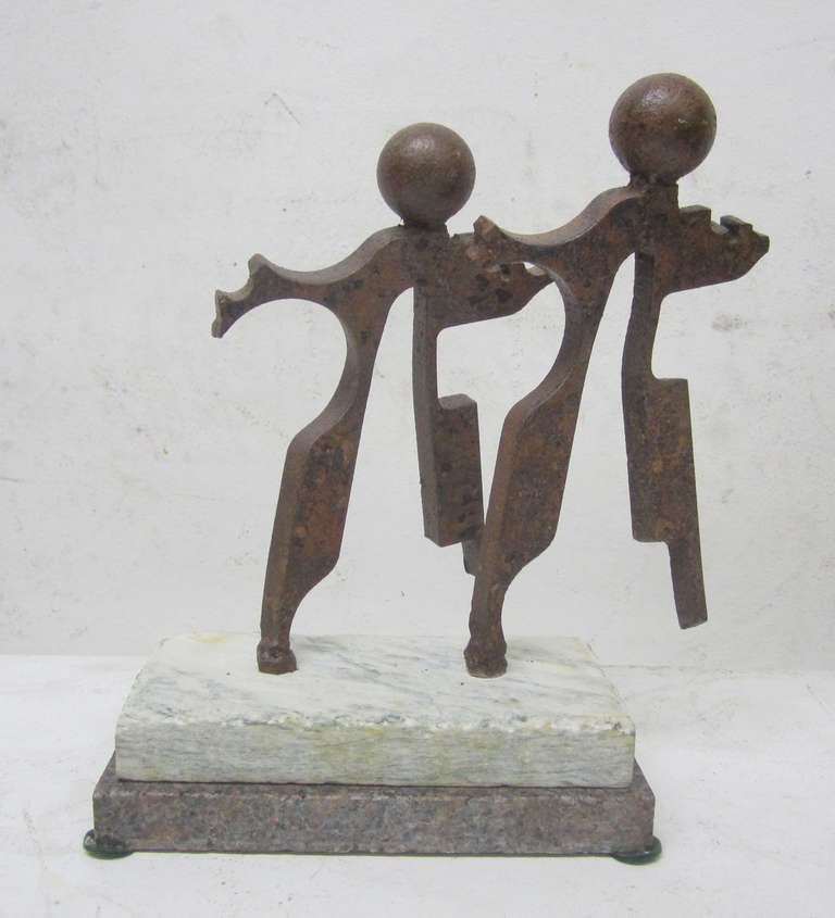 This playful sculpture features a pair of cast iron figures mounted atop two slabs of stone. Each figure rotates 360 degrees individually allowing the viewer to change the piece innumerable ways. Signed beneath 