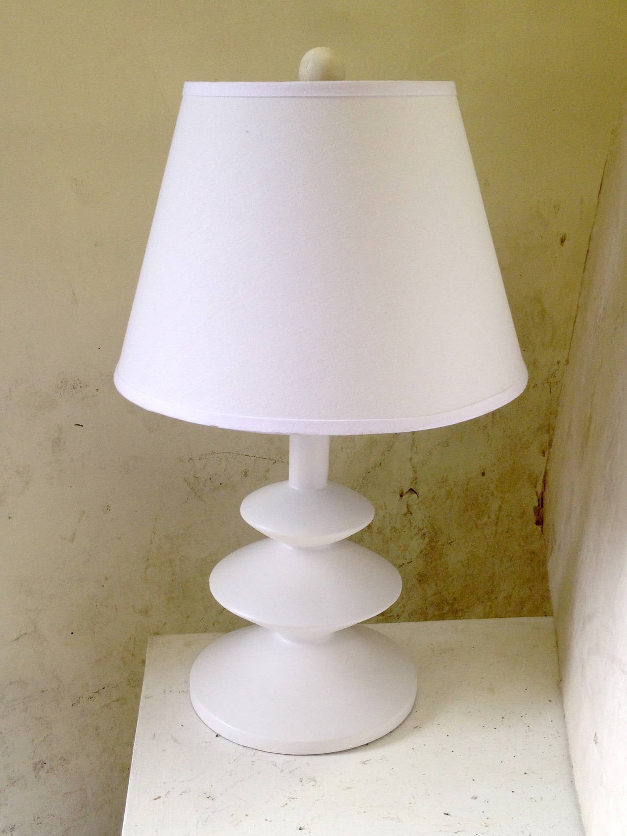 The playful, structural design of this pair of table lamp safter a design of Alberto and Diego Giacometti for Jean Michel Frank. The bases, rendered in heavy plaster and coated with opaque white paint, are comprised of three stacked saucers in