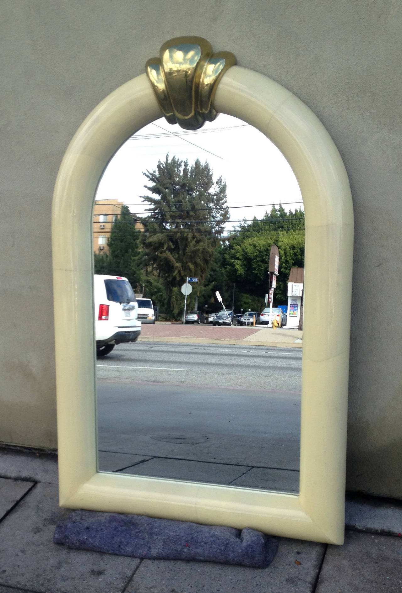 This chic 1970s mirror features a goat skin frame and a large brass detail at the top.