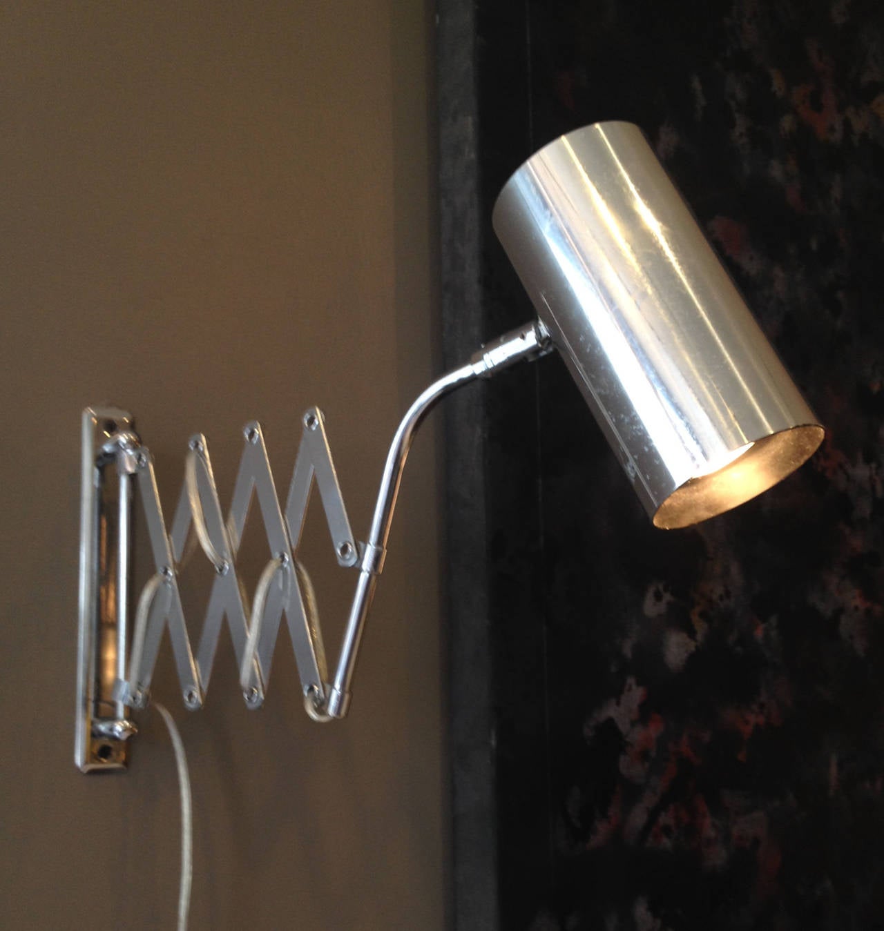 This Koch and Lowy accordion sconce attaches to the wall via a chrome panel. The cylindrical shade, which can be rotated to point in any direction, is found at the end of an extendable arm, rendering this elegant sconce extremely functional. 
The