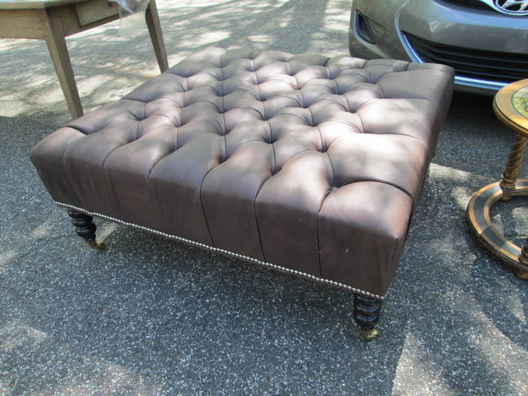 Oversized leather tufted ottoman,
with nailhead detail and beautiful ebonized turned leg with elegant castors.