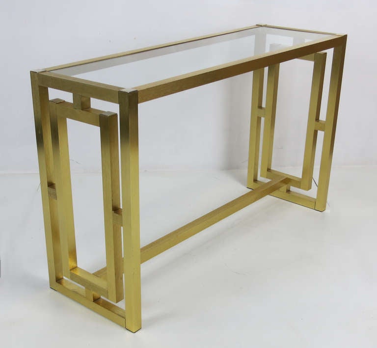 Hollywood Regency style Console in bright brushed Brass anodized aluminum with inset glass top.