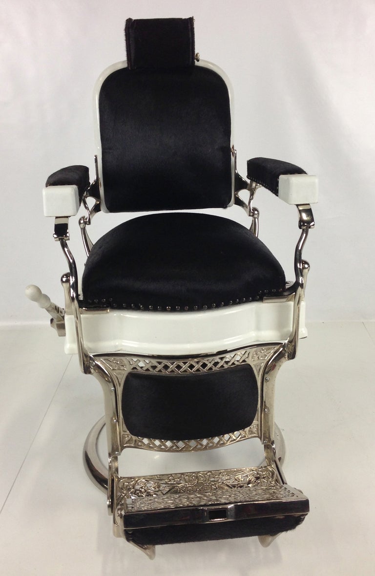 Classic Antique Porcelain-over-Cast Iron Barber's Chair with Nickel plated hardware and trim by Ernest Koken.  The chair has been completely restored with new Nickel plating and hair-on cowhide upholstery.  The chair swivels, is height adjustable,
