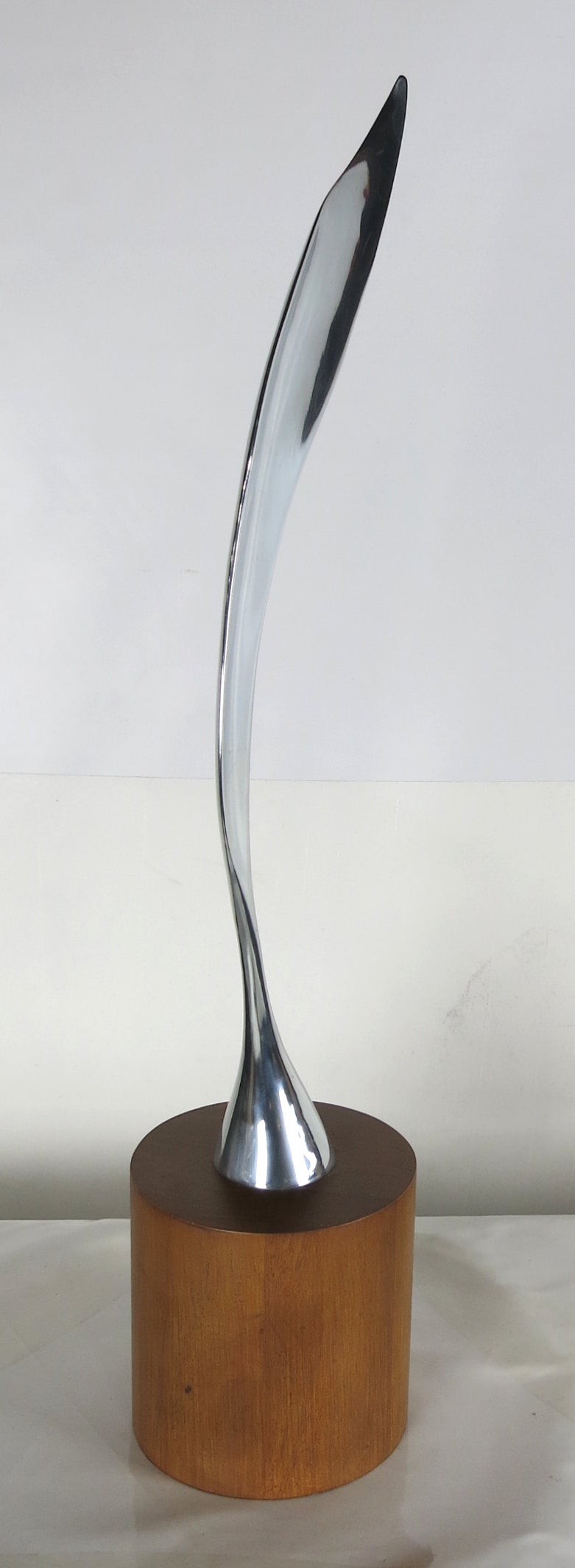 Polished aluminum feather sculpture mounted on a cylinder form walnut base in the manner of Brancusi.