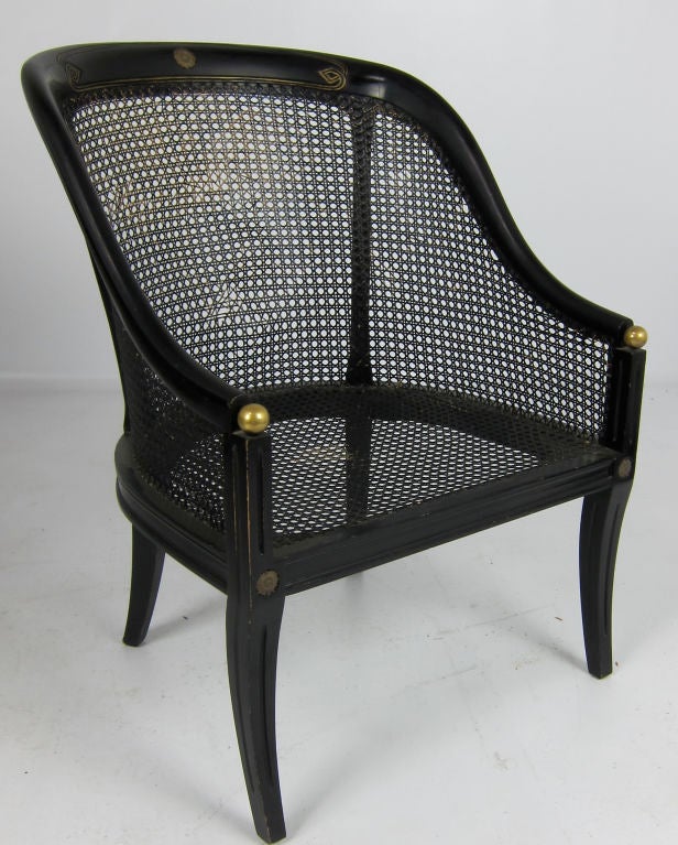 Pair of ebonized Spoonback armchair with gilt carving. The saber form front legs are surmounted with brass spheres. Seat height to the deck is 13.5