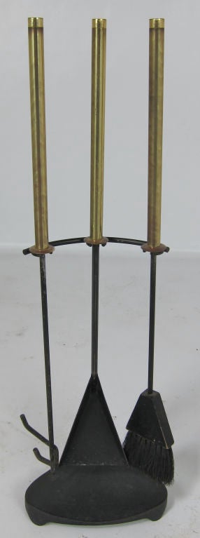 Set of Brass handled fireplace tools hung on a sculptural iron stand.  The long brass handles are nicely darkened and patinated from age.