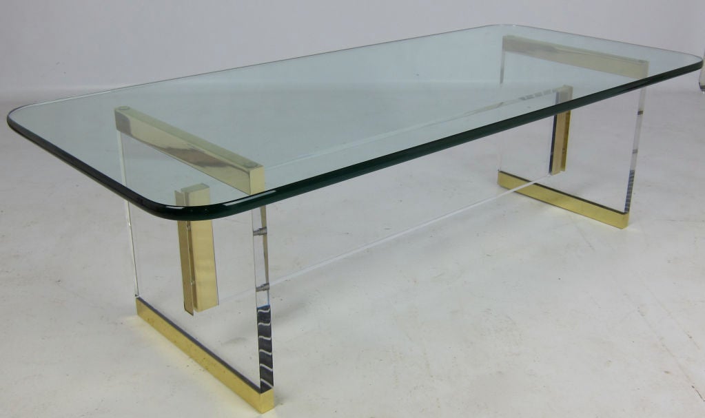 Brass capped thick Lucite supports with slab stretcher.  Brass end trim is beautifully mortised flush into the Lucite. The top is 3/4