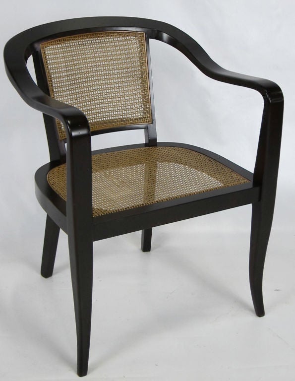 Pair of sinuously carved armchairs with caned seats and backs by Edward Wormley for Dunbar.  The chairs have been completely restored; frames have been refinished in deep brown hand rubbed lacquer and the frames have been freshly re-caned.