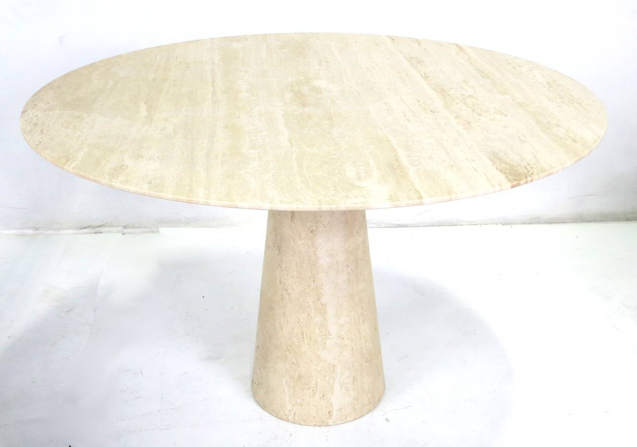 Striking travertine dining table with knife edge top and tapering one-piece pedestal base.
