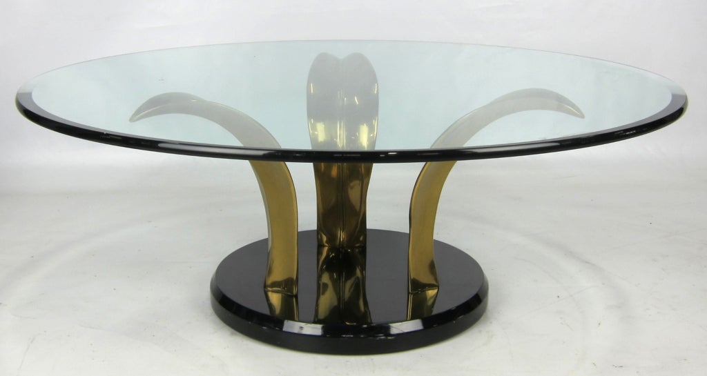 Three curved Bronze Palm leaves on a black lacquer base supporting a thick glass top.  Overall diameter of the base alone is 32