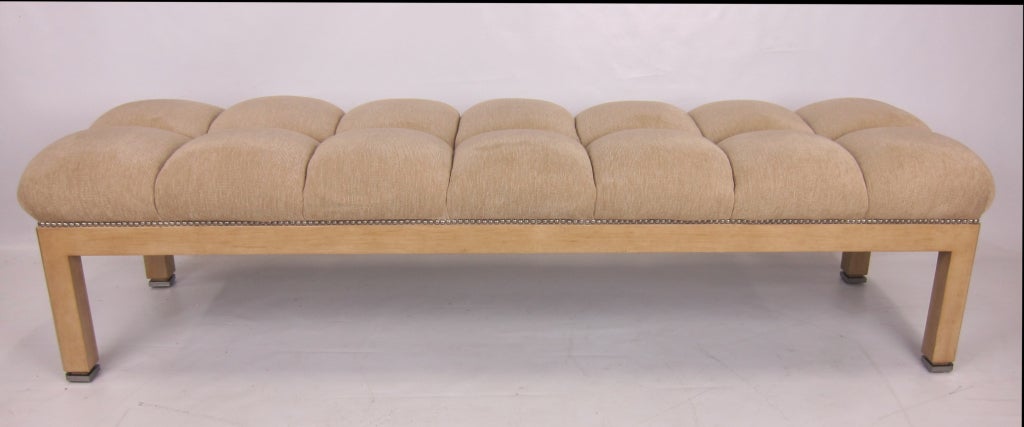 Large scale bench with antiqued faux Ivory lacquer frame and brushed steel feet.  The super comfortable seat is deep biscuit tufted.