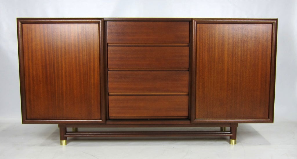 Large Mahogany Cabinet with sliding doors flanking a center section of drawers attributed to Paul Laszlo for Brown Saltman.  This piece would make a great Buffet/Sideboard or a Gentleman's Wardrobe.  The cabinet is raised on large cylindrical legs