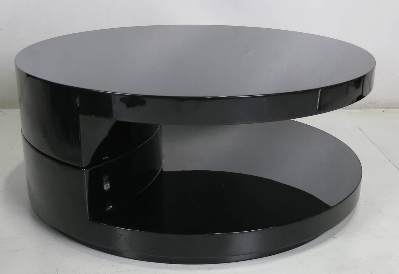 Super sleek and low articulating top coffee table in black lacquer. The top swivels 360 degrees to a detente at 180 degrees. A sublime design with a beautiful polyester lacquer finishes that swivels smoothly in both directions. A heavy, top quality