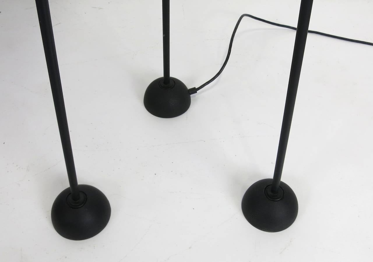 Memphis style blackened steel and brass torchiere. The feet and supports are smooth, raw blackened steel surmounted by a solid raw un-lacquered brass reflector. Lit by a single halogen bulb with ball-finial dimmer on the shade. Top quality materials