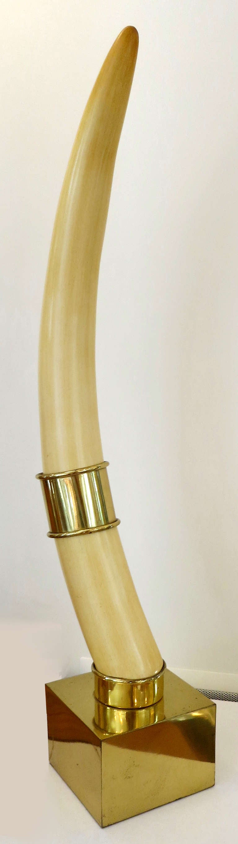 Pair of faux Ivory Tusks with brass cuffs mounted on polished brass bases by Chapman.