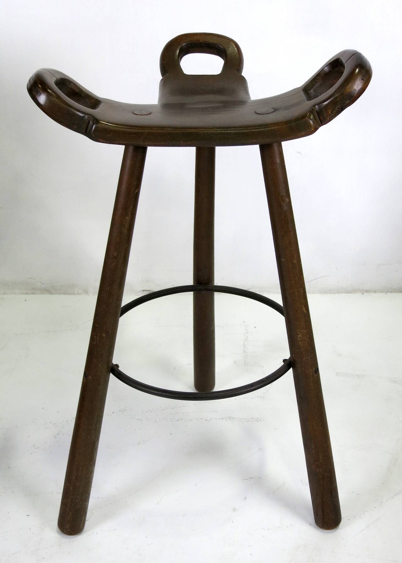 Handsome set of three tripod bar stools with hand-wrought iron footrest.