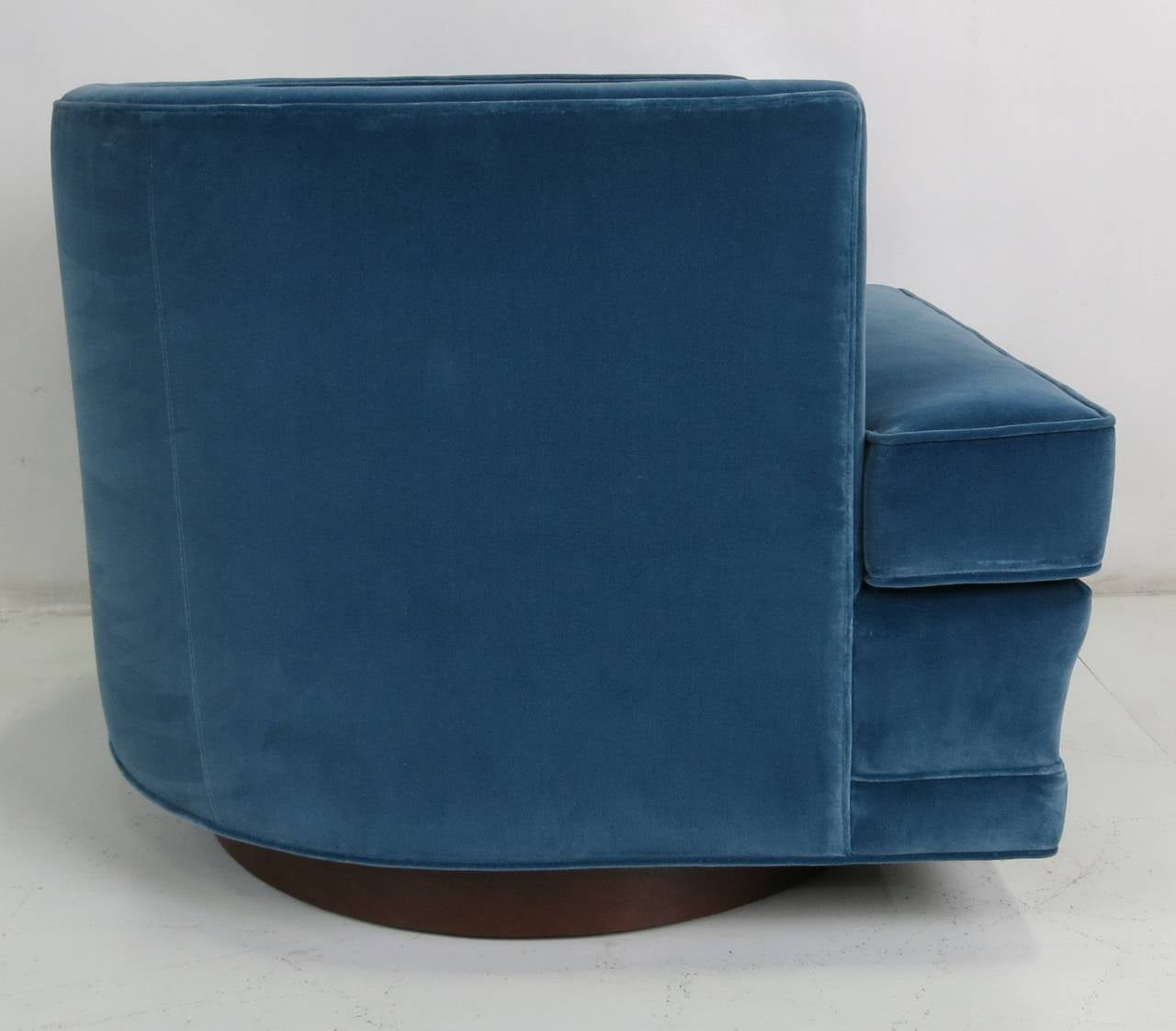 Fine pair of swivel lounge chairs freshly upholstered in luxurious teal velvet. The round walnut swivel base has been freshly refinished and the swivel plate has been replaced with a new heavy duty example.