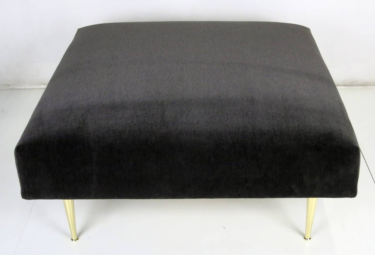 Luxurious custom velvet ottoman raised on tapered polished brass legs by Antiques du Monde. The brass legs have been mirror polished and lacquered.